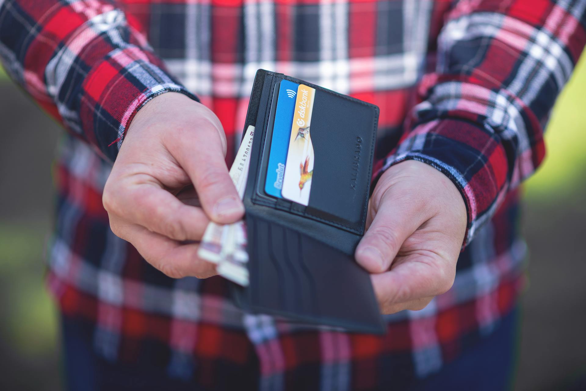 A close-up of hands holding an open wallet revealing credit cards