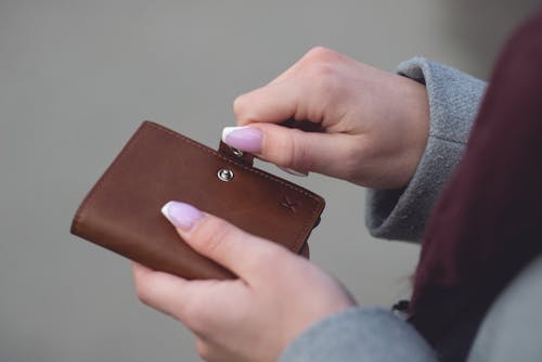 Person Closing a Brown Leather Wallet
