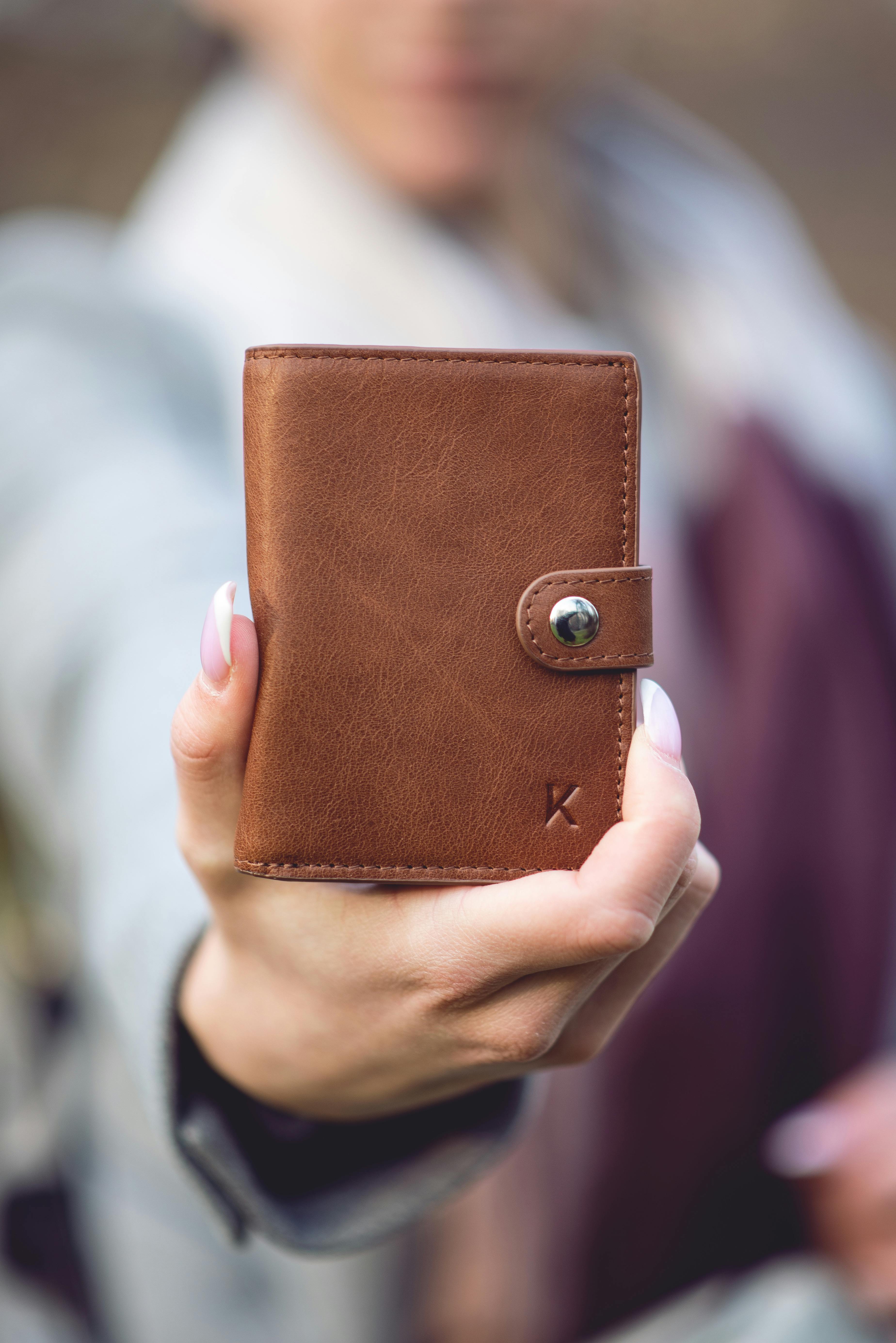 close up shot of a person holding a brown wallet