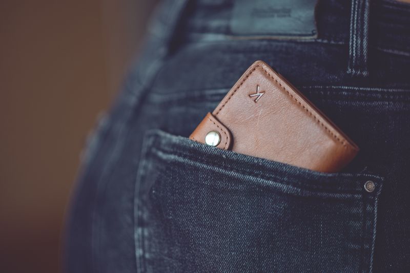 A stylish brown leather wallet partially visible in a jeans back pocket.