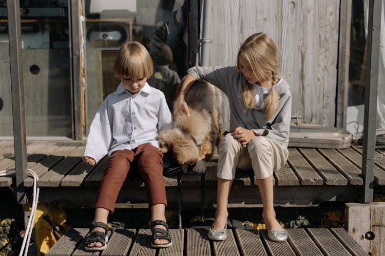 A Girl And Boy Sitting With Dog