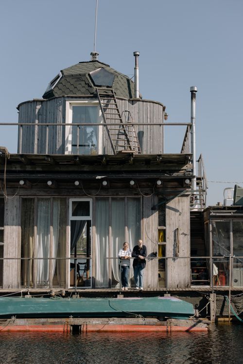 Free A couple standing on a houseboat deck, enjoying a sunny day by the water. Stock Photo