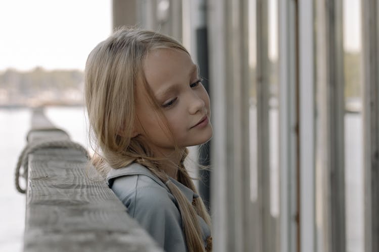 A Girl Leaning On A Wooden Railing