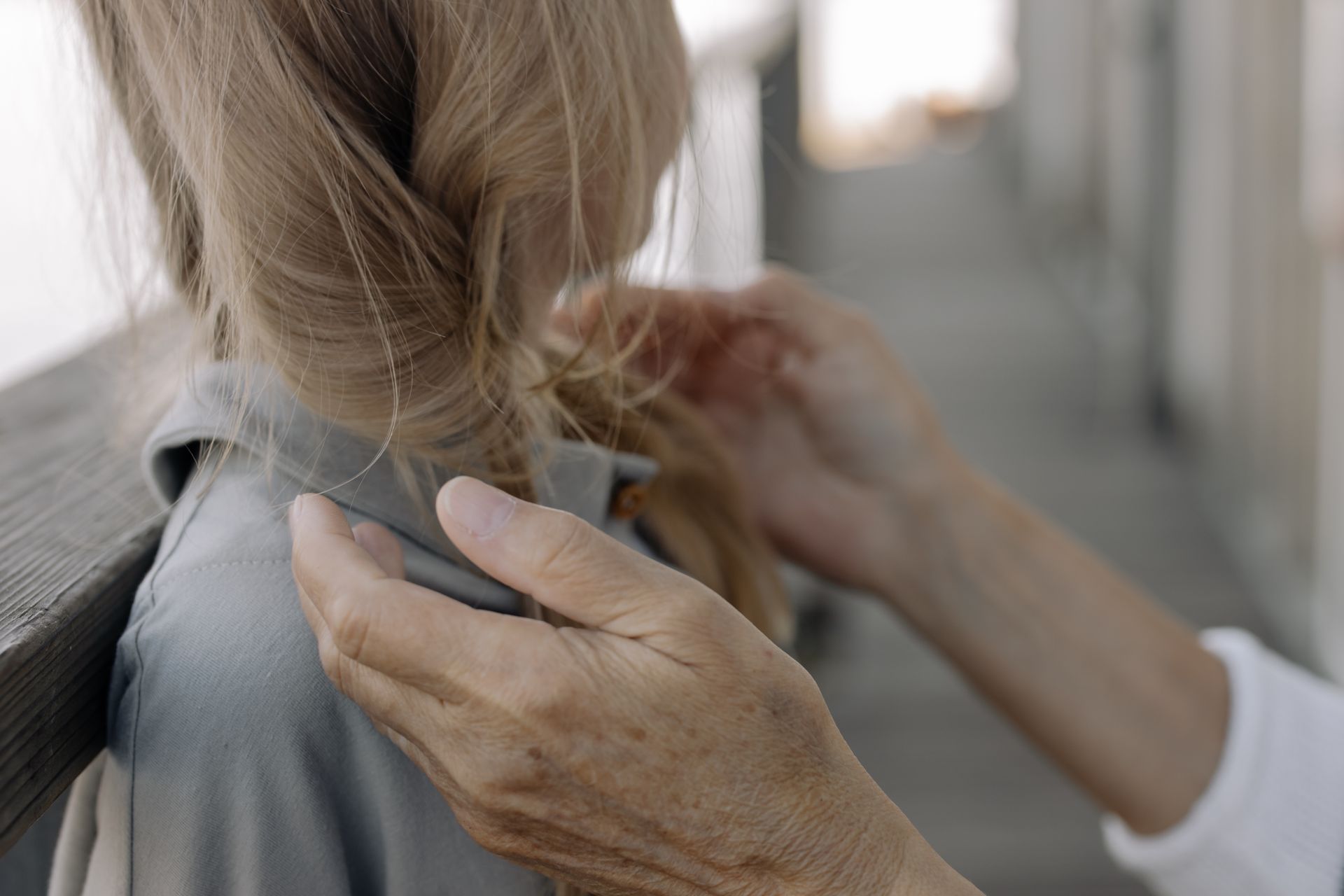 Close-up of a child's hair being gently braided outdoors. A moment of care and bonding.