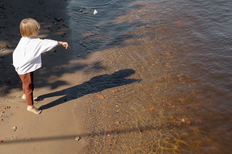 A Boy Throwing Stone Into The Sea