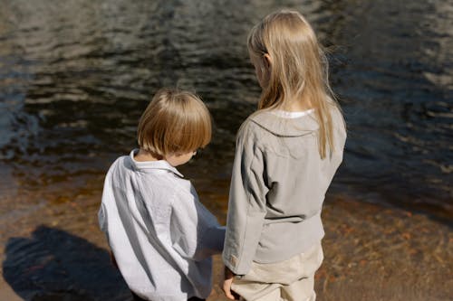 Back View of Siblings Standing Near a River