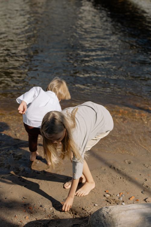 Free Two children enjoying a sunny day by the riverside, collecting stones. Stock Photo