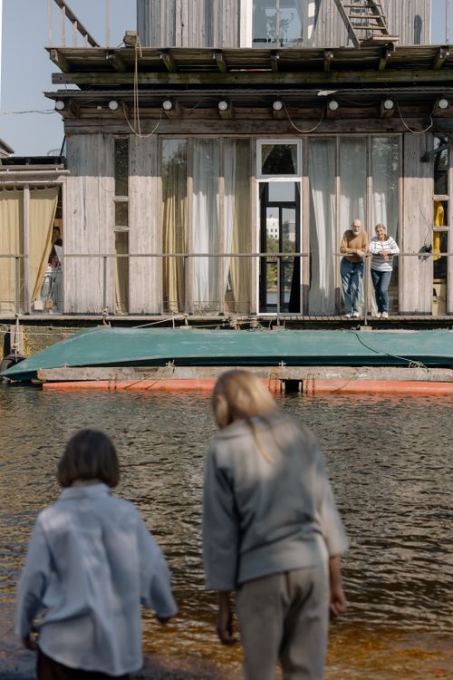 Free A serene summer moment with family by a floating house on the river. Stock Photo