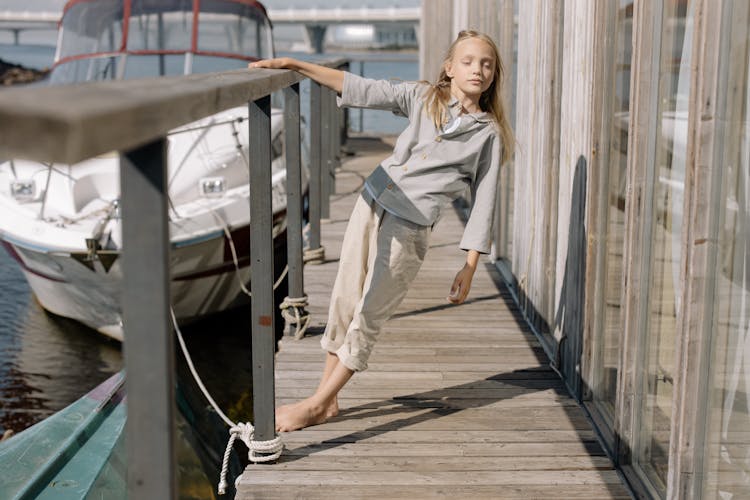 A Girl Holding On A Wooden Railing While Leaning Back