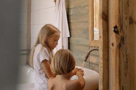 Two young children wash their hands in a bathroom, promoting hygiene and cleanliness.