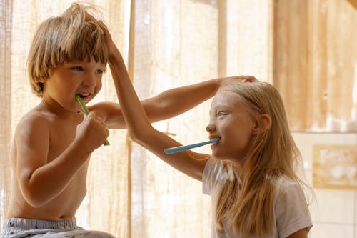 Free Brother and Sister Brushing Their Teeth Stock Photo