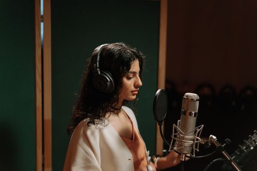 Free A female singer recording vocals in a professional music studio with a microphone. Stock Photo