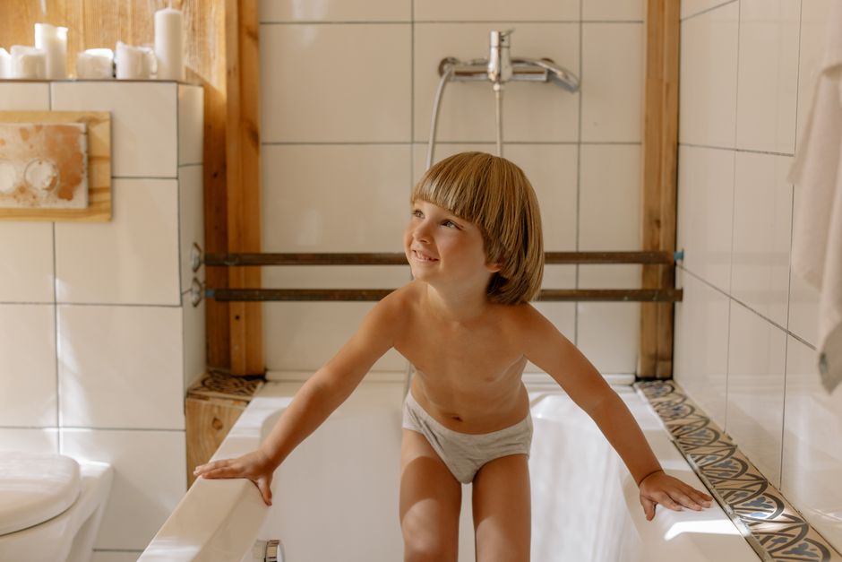Adorable young child smiling in a modern bathroom, enjoying bathtime.