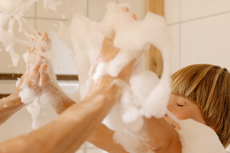 A Person And A Kid With Soap Suds On Hands
