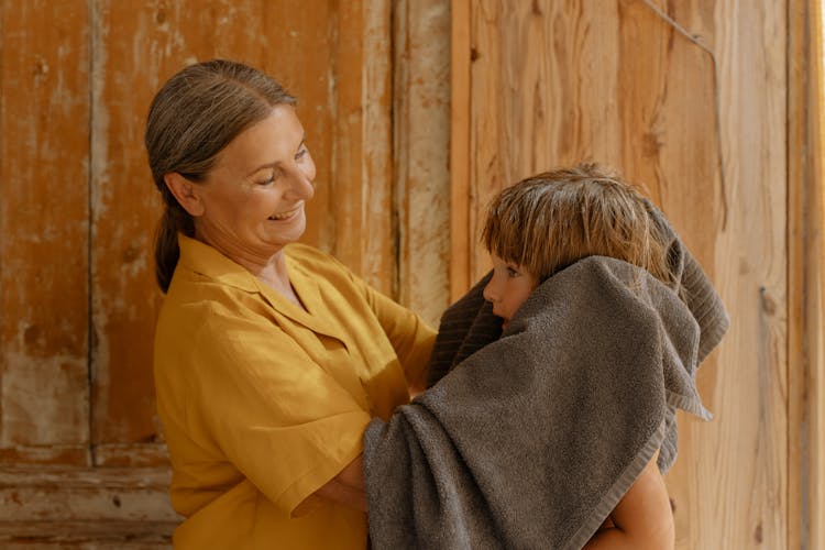 A Woman Drying The Hair Of A Boy With A Towel