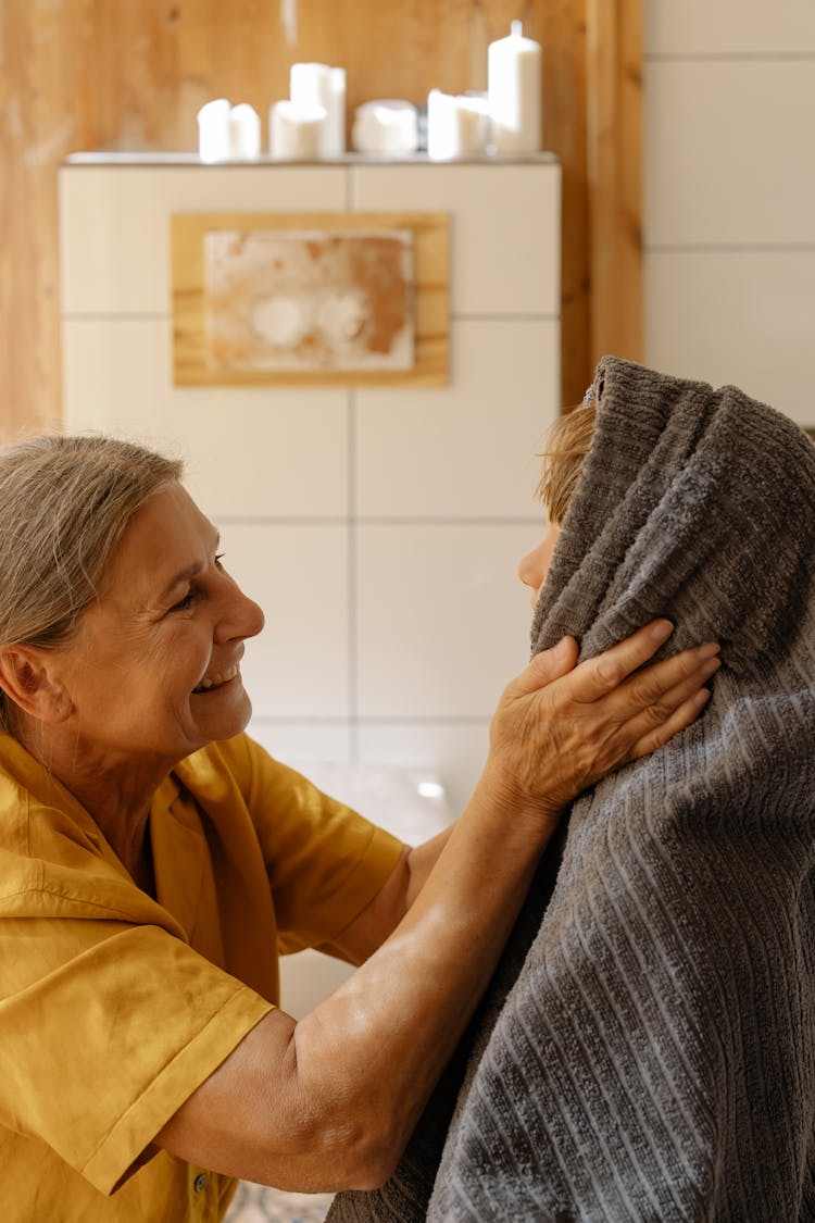 A Woman Drying The Hair Of A Boy With A Towel