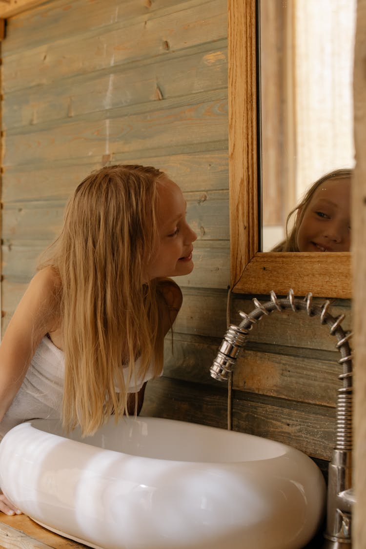 
A Girl Looking At The Mirror In Bathroom