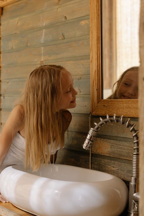 A Girl Looking at the Mirror in Bathroom · Free Stock Photo