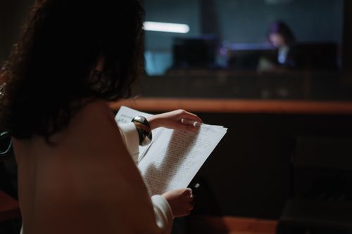 Free Woman in recording studio holding sheet music, preparing to perform. Stock Photo
