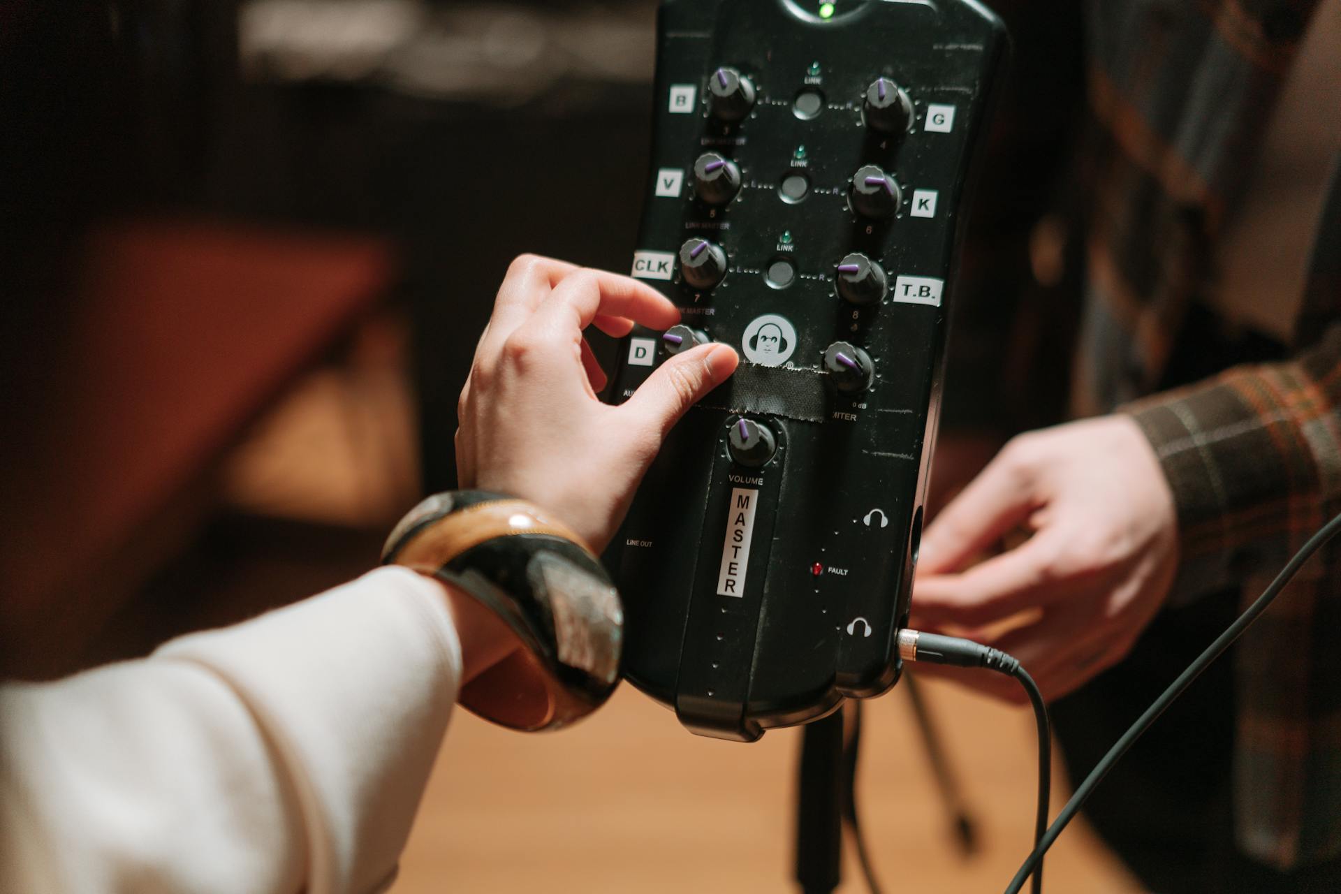 Close-up of hands adjusting audio device controls for music production and recording.