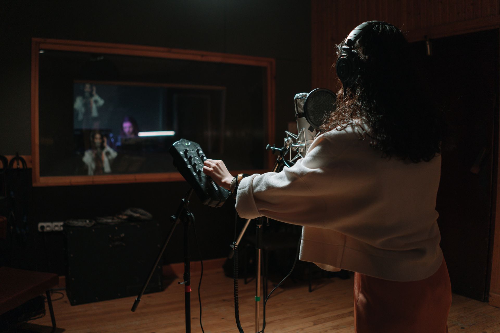 Woman singing in a professional music studio with condenser microphone.