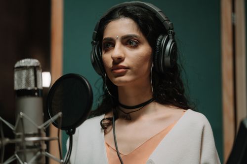 Free Female singer recording vocals in a professional music studio wearing headphones. Stock Photo