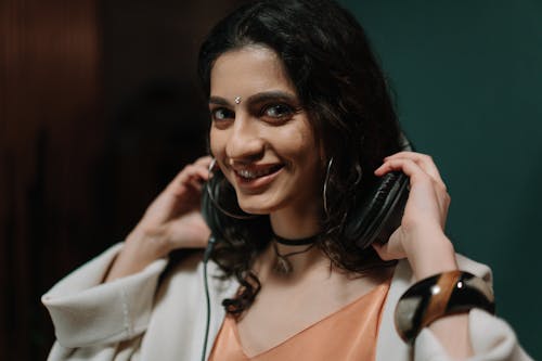 Woman Holding Black Headphones Smiling