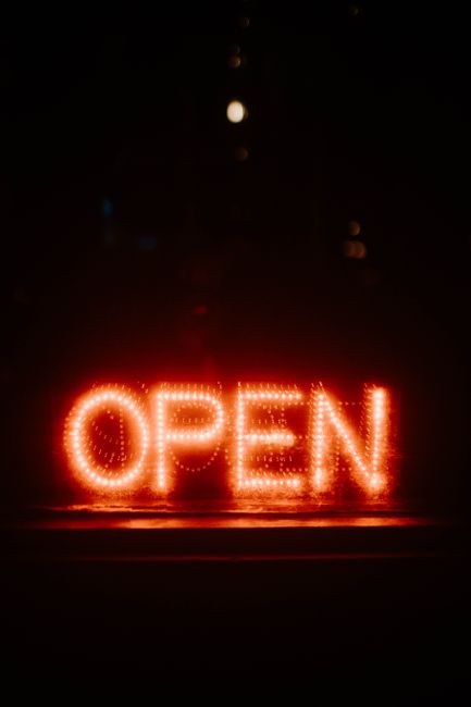 Bright neon open sign glowing against a dark background, perfect for business promotion.