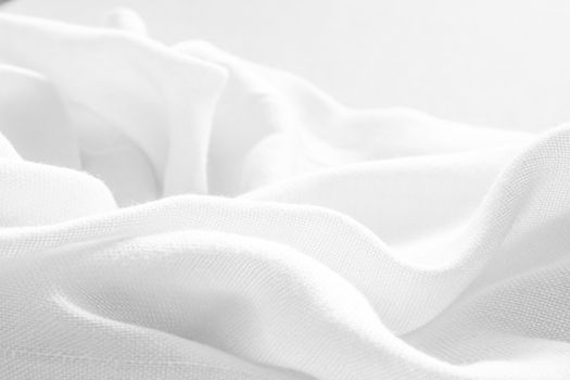 Close-up of a smooth white textile with delicate folds, creating an elegant texture.