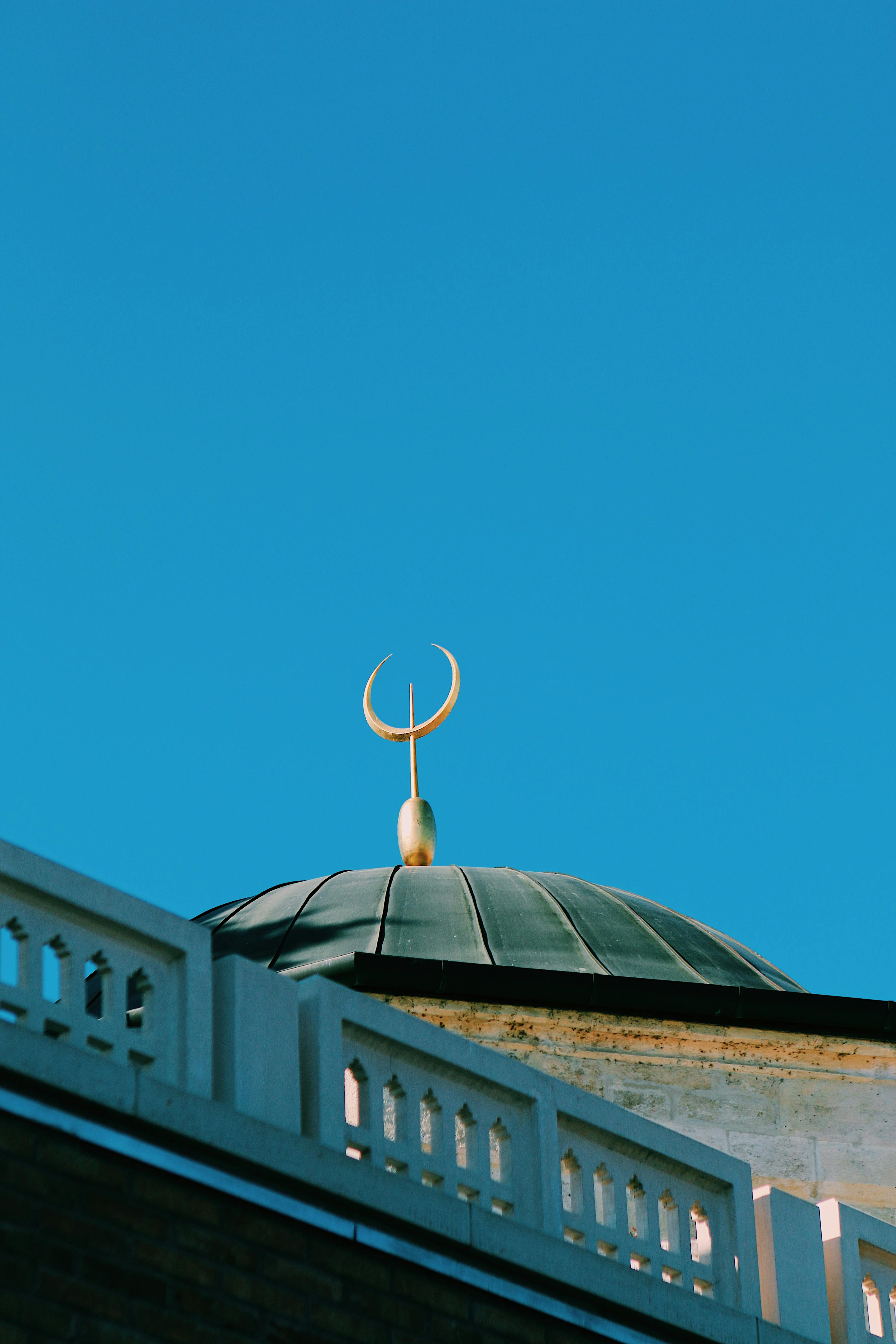 Low-angle shot of a mosque dome with a crescent moon against a clear blue sky in Budapest, Hungary.