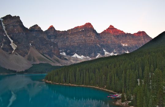 A breathtaking view of Moraine Lake and surrounding mountains at sunset in Banff National Park, Canada.