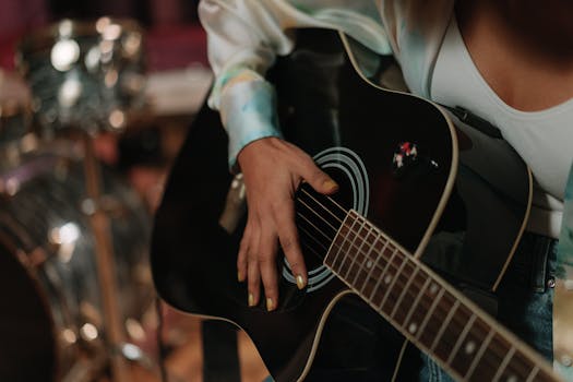 A woman strums an acoustic guitar indoors, showcasing detailed hand positioning.