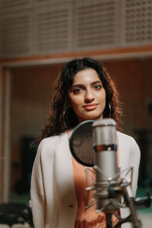 Free A woman singing in a professional studio, capturing her lively expression and musical passion. Stock Photo