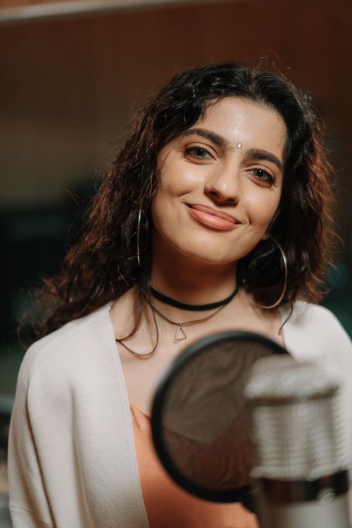 Free Portrait of a smiling woman recording music in a studio with a microphone. Stock Photo