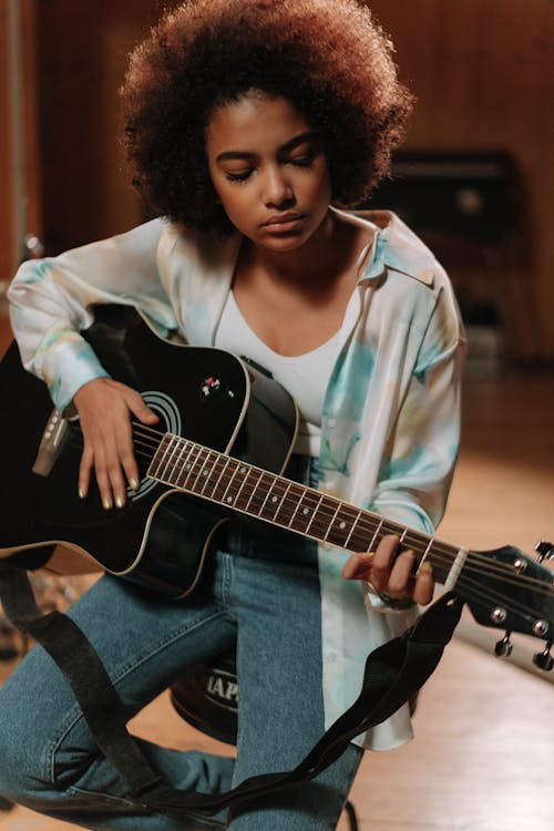 A Woman Playing a Guitar inside a Music Studio