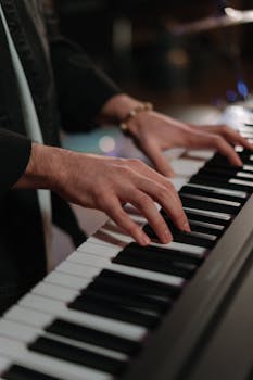 A musician's hands playing a piano keyboard indoors, showcasing musical skill and artistry.