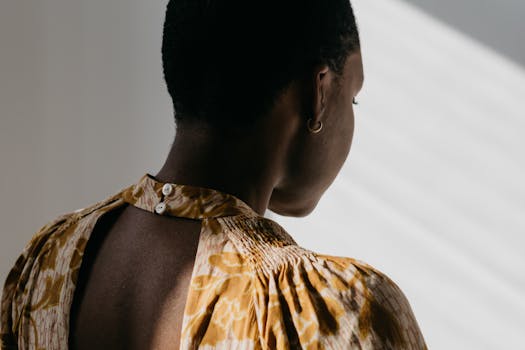 Artistic capture of a woman from behind in a sunlit room, showcasing texture and shadow.