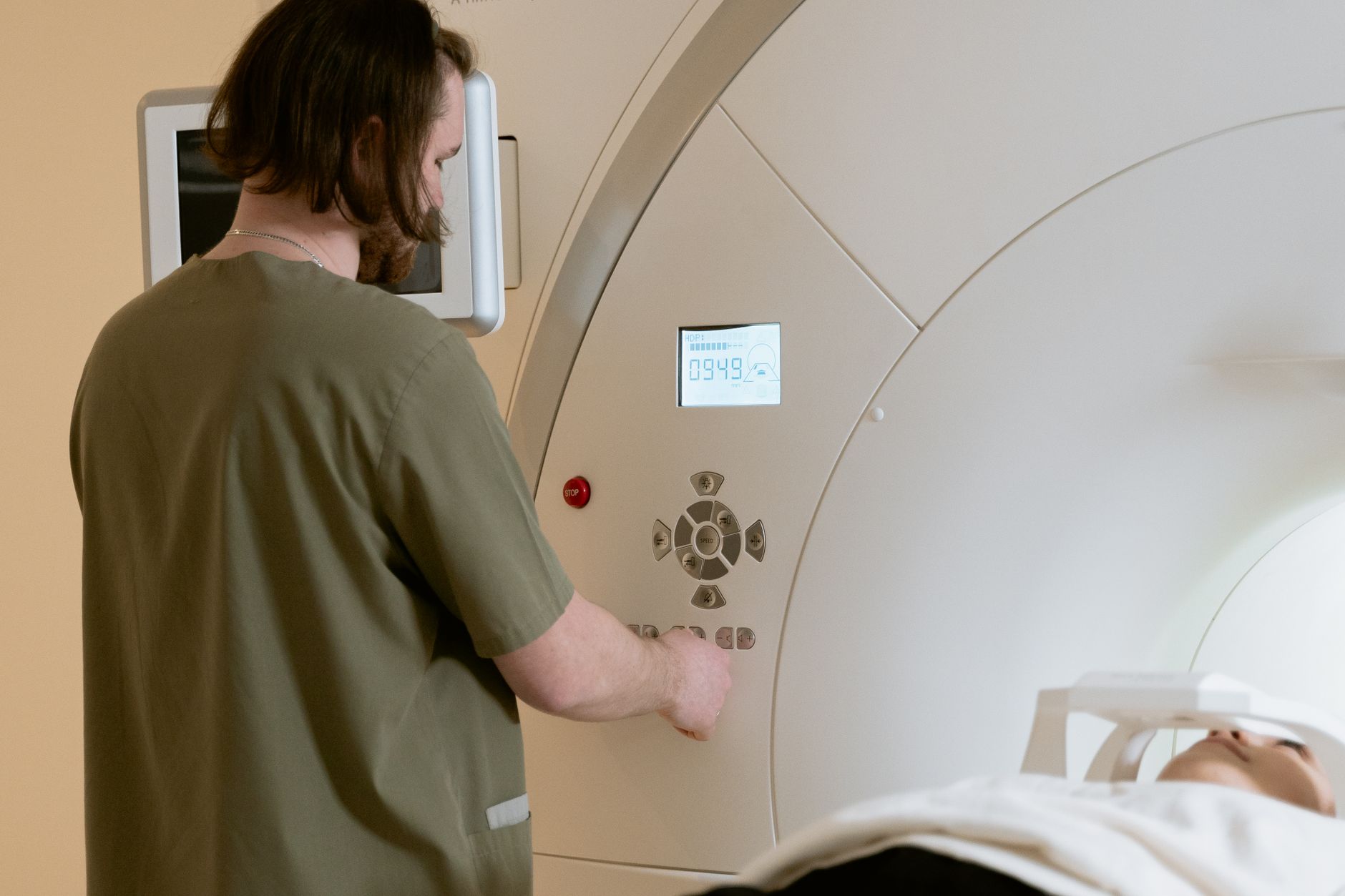 A healthcare worker operates an MRI scanner with a patient in a medical facility.