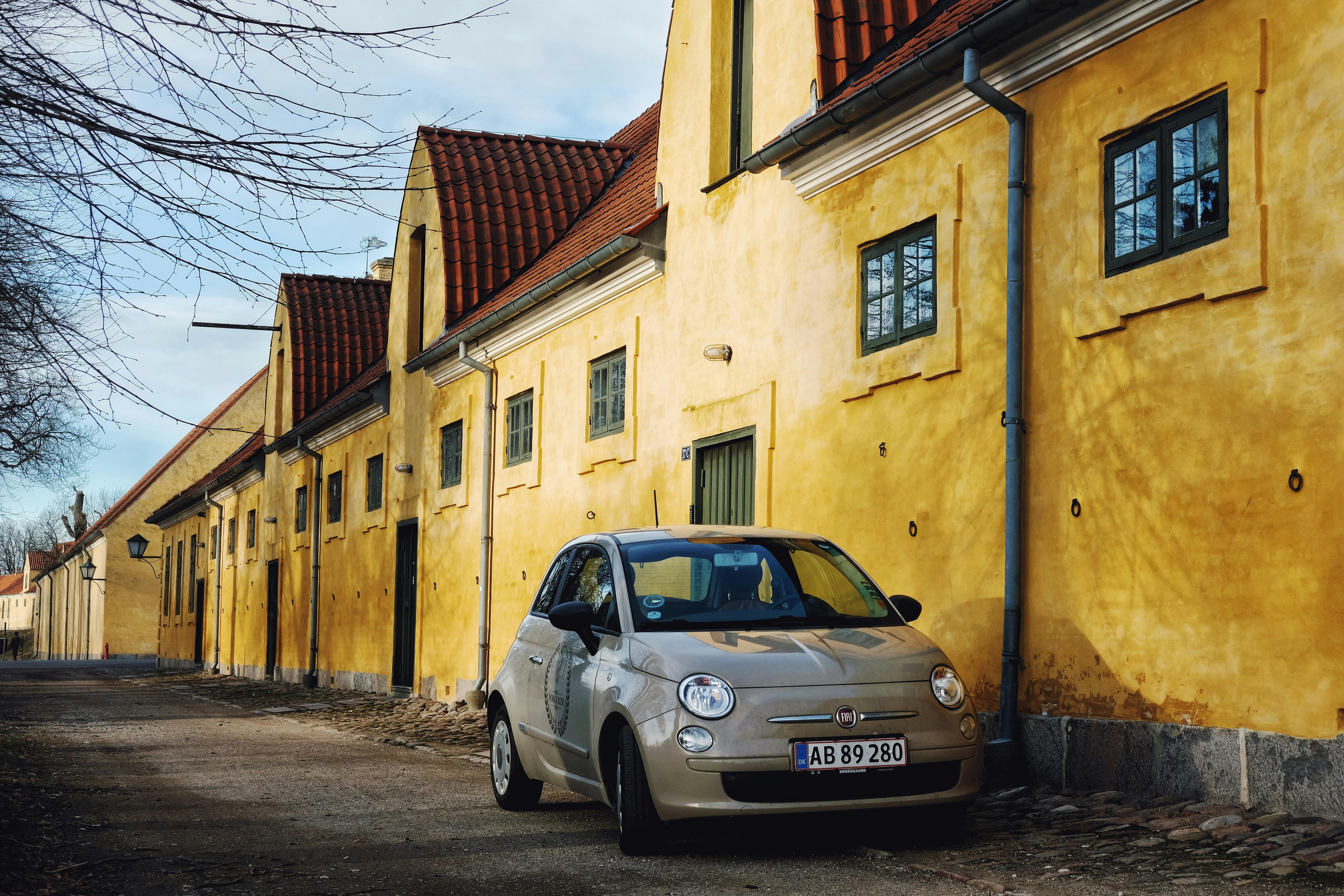 a hatchback car parked beside a yellow building
