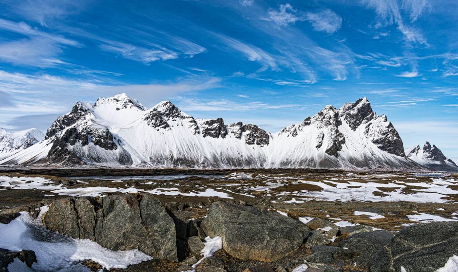 Snow-covered mountains under a vibrant blue sky in Iceland's winter landscape, offering stunning natural beauty.