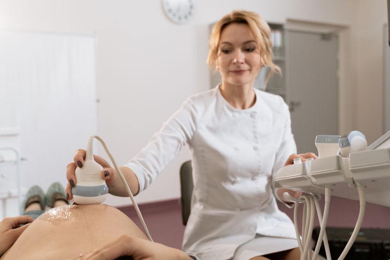 Healthcare professional performing ultrasound examination on pregnant woman in medical clinic.