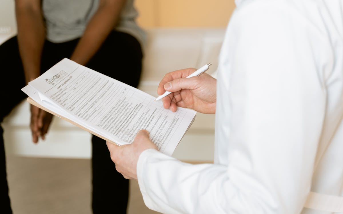 Healthcare professional reviews medical form during patient consultation in a clinic setting.