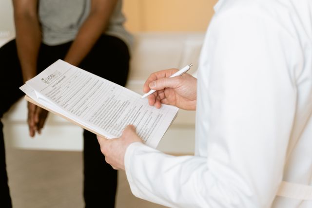 Clinician taking notes during a confidential consultation