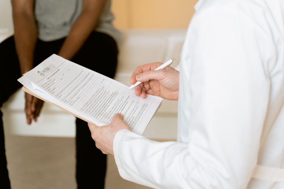 Doctor reviewing a medical form with a patient — ibogaine treatment for depression requires full medical screening including EKG and blood panel before any ceremony