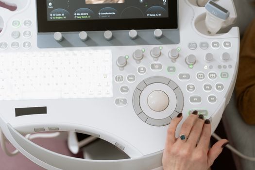 Close-up of a medical professional operating modern ultrasound equipment for diagnosis.