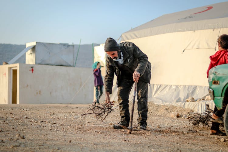 An Elderly Man In Black Leather Jacket Picking Sticks