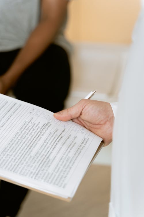 Photo Of Person Holding Paper And Pen 