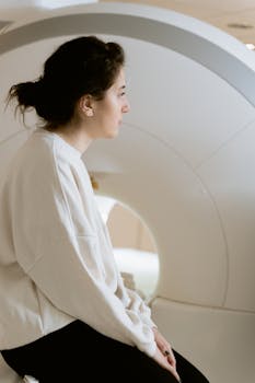 A woman seated near a CT scanner, capturing a medical and clinical environment.
