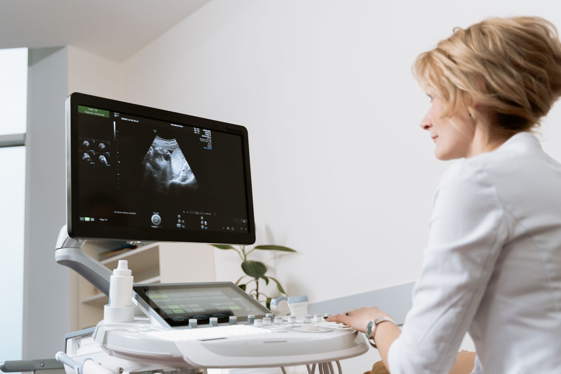 Médica usando ecógrafo en clínica moderna.