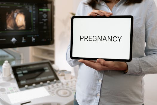 A doctor holding a tablet with 'Pregnancy' near an ultrasound machine. Medical consultation setting.
